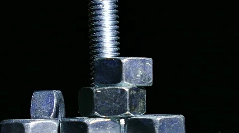 Group of bolt with  nuts rotates against  dark background. 4K  close up centre s Stockbeeldmateriaal 61458165