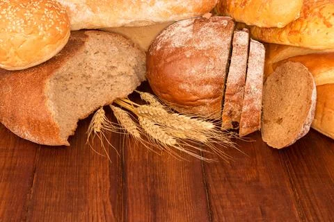 Group of bread on wooden table with wheat ears Stock Photos