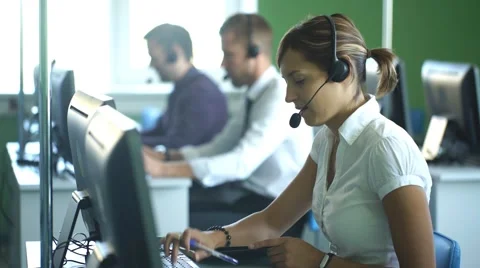 Group of business colleagues with headsets using computers at office desk Stock Footage 67669592