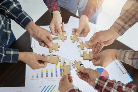 A group of business people assemble jigsaw puzzles, the concept of cooperatio Stock Photos