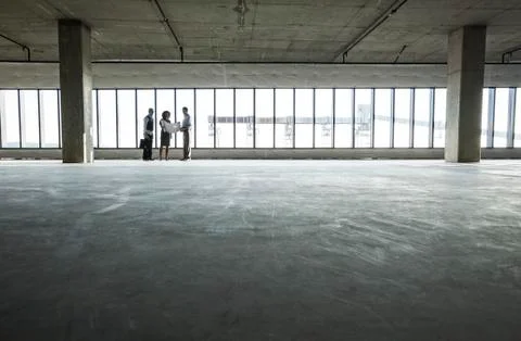 Group of business people looking at a new empty raw office space. Stock Photos