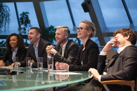 A group of business people sitting at a table discussing and laughing. Stock Photos
