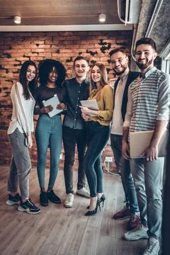 Group of businesspeople using wireless technology together while standing nea Stock Photos
