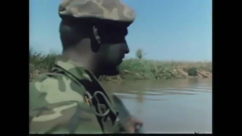 A group of camouflaged US Navy SEALs paddle a boat on a river in 1969. Stock-Footage 157214874