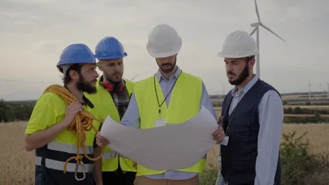 Group of caucasian engineers male checking wind turbines using plans. Renewable Stock Footage 243433340