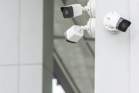 Group of CCTV security cameras outside on modern building wall in city Foto stock