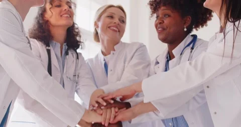 Group of cheerful female doctors stacking hands and clapping in medical office 動画素材 306002225