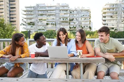 Group of cheerful multiracial students together happily looking at laptop Stock Photos