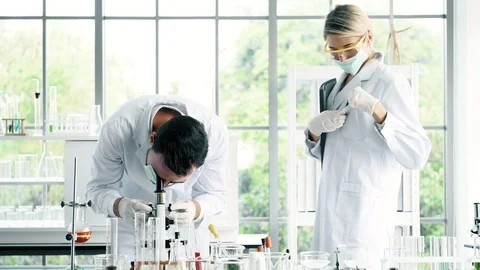 Group of chemist working in a lab, looking at microscope. Stock Footage 99014595