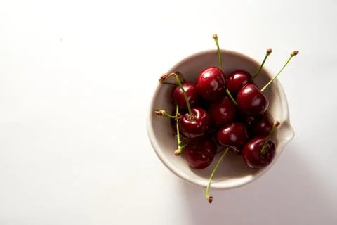 Group of cherry in a small cup on a white background with shadows. Close-up.  Stock Photos