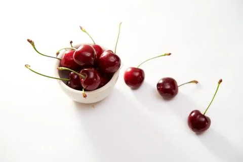 Group of cherry in a small cup on a white background with shadows. Close-up.  Stock Photos