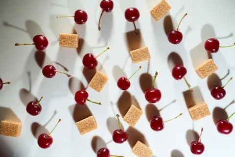 Group of cherry on a white background with cubes of reed sugar and shadows Stock Photos