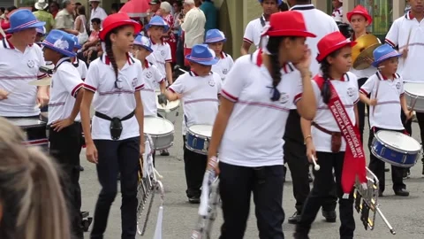A group of children are marching in a parade, wearing white shirts and red hats Stock Footage 272657075