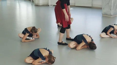 A group of children in a choreography class do stretching while sitting on the Vidéo 96305833