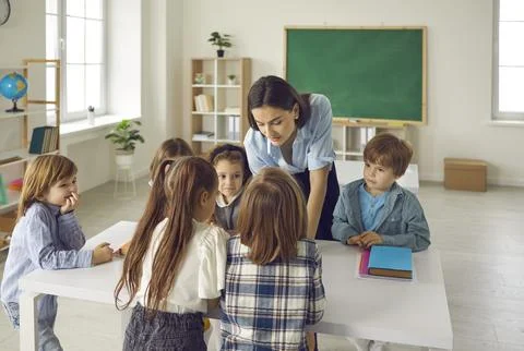 Group of children complete a task together with a young female primary school Fotos de archivo