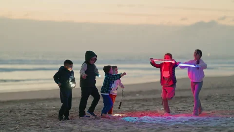 Group of children dancing on the beach with led lights at dusk Stock Footage 330496551