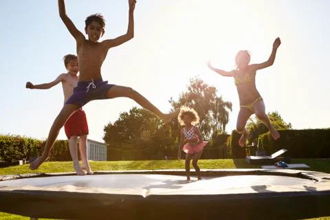 Group Of Children Having Fun Jumping On Outdoor Trampoline Stock Photos