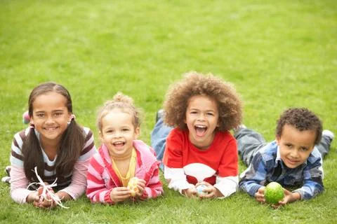 Group of children laying on grass with easter eggs Stock Photos
