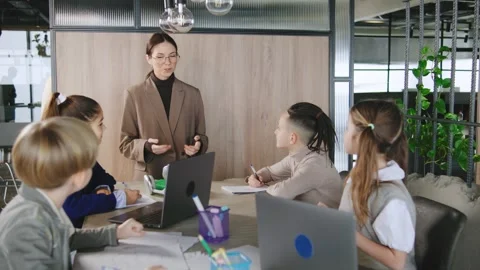 Group of children learning from a teacher in a modern classroom setting during a Stock Footage 331306019