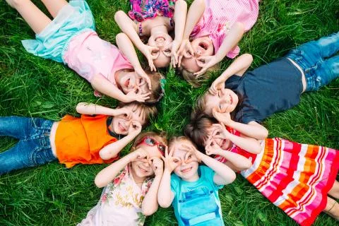 A group of children lying on the green grass in the Park. The interaction of the Stock Photos