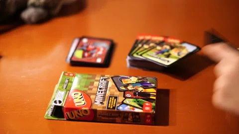 Group of children playing a Minecraft Uno card game on a wooden table Stock Footage 228679626