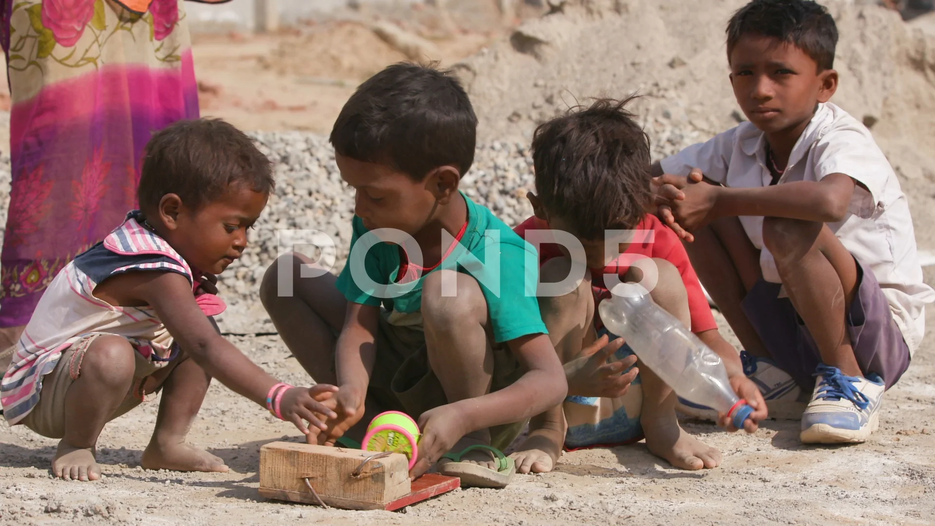 Group of children playing with toys with a women standing behind them