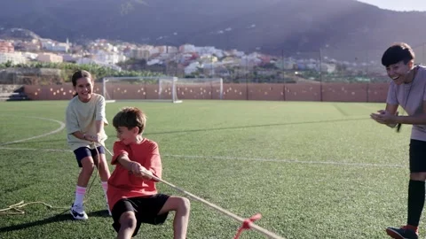 Group of children playing tug-of-war outdoors - Sport team kids having fun Stock Footage 253189147