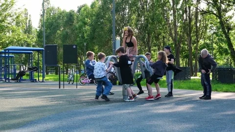 A group of children ride a small carousel in the park on the playground. 스톡 동영상 242655047