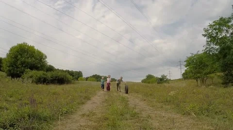 Group children running down the hill in a meadow and roll the wheel. slow motion Video stock 53466985