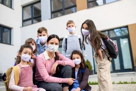 Group of children, teacher with face masks outdoors at school after covid-19 Stock Photos