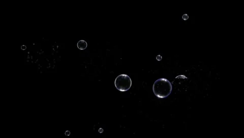 Group of clear soap bubbles floating and bursting against a black background Video stock 342112803