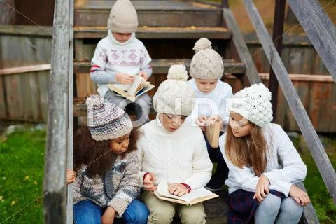 Group of clever kids reading books outdoors Stock Photos