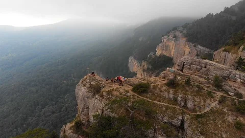 A group of climbers enjoy the views while sitting on the edge Stock Footage 99258284