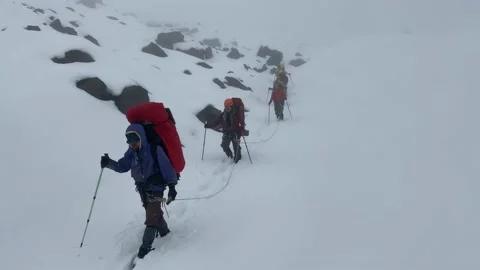 Group of climbers walk in a bundle along a snow-covered mountain trail Stock Footage 141050558