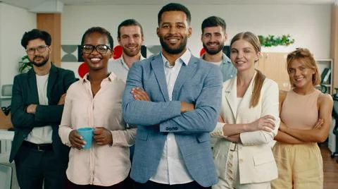 A group of co workers are in a very nice looking office smiling and crossing Stock Photos
