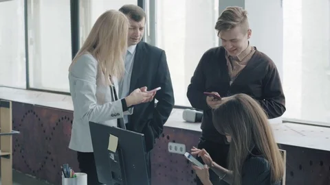 A group of colleagues are having fun talking with each other using smartphones Stock Footage 124329712