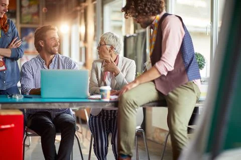 A group of colleagues is chatting while having a break at work in the office Stock Photos