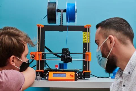 A group of colleagues collaborate in a lab while testing a 3D printer 写真素材
