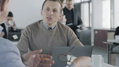 A group of colleagues communicate with each other at the desktop. In the Stock Footage 124705573
