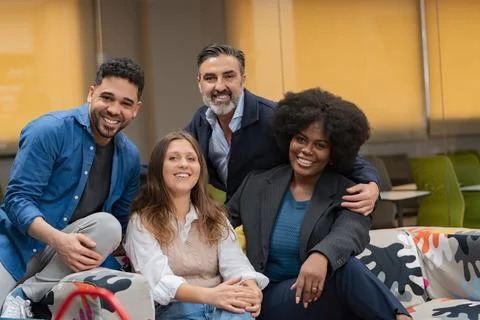 Group of colleagues smiling on a patterned sofa. Foto stock