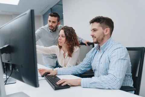 A group of colleagues trying to solve a problem on a computer Stockfoto's