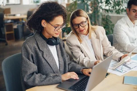 Group of colleagues working together with documents while sitting on office desk Stock Photos