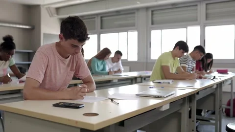 Group of college students doing an exam sitting in a row in class Stock Footage 207367199