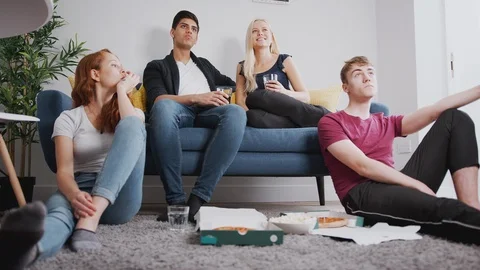 Group Of College Students In Shared House Watching TV And Eating Pizza Stock Footage 119831546