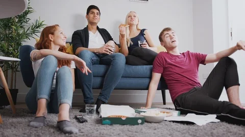 Group Of College Students In Shared House Watching TV And Eating Pizza Stock Footage 119831615