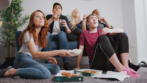 Group Of College Students In Shared House Watching TV And Eating Pizza Stock Footage 119831647