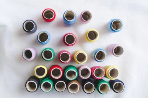 Group of colored thread spools on white cotton cloth, top view Foto stock