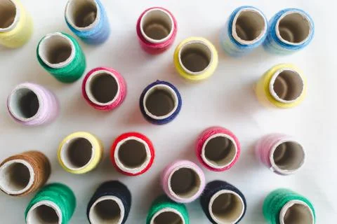 Group of colored thread spools on white cotton cloth, top view Stock Photos