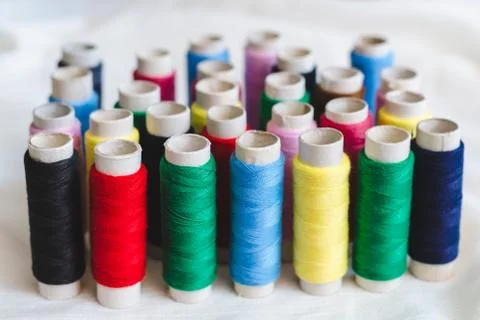 Group of colored thread spools on white cotton cloth Stock Photos
