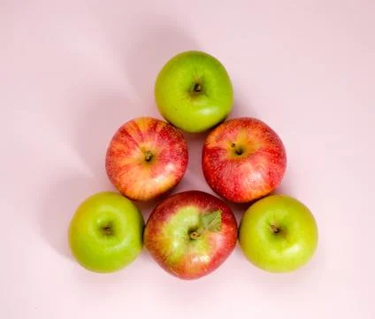 Group of colorful apples in a shape of triangle isolated on pink background. Stock Photos